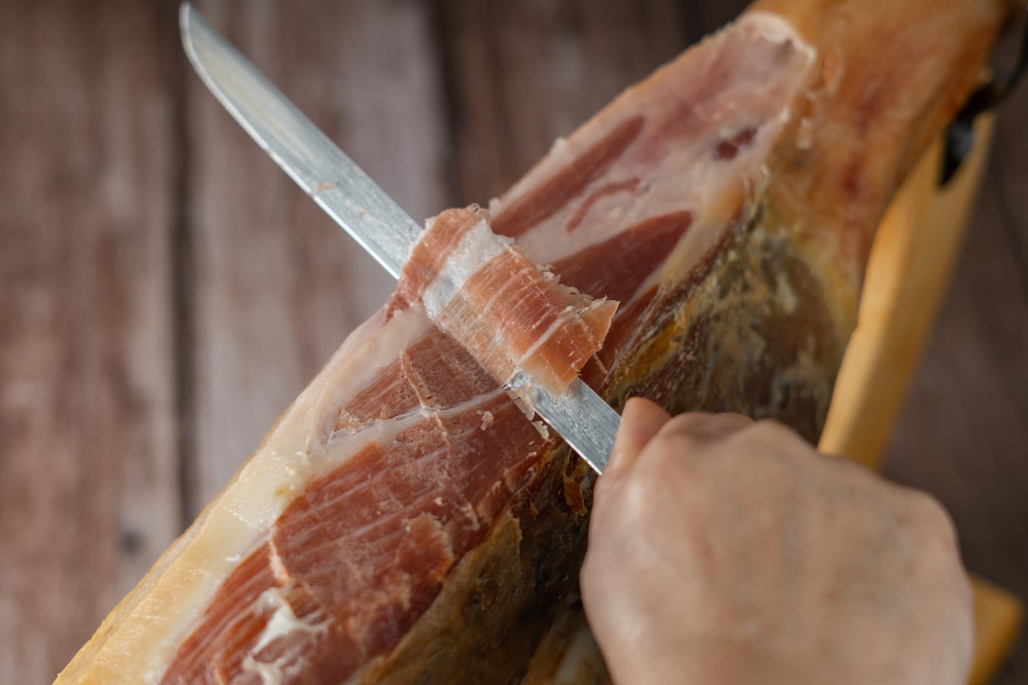 Persona usando un cuchillo jamonero para cortar jam&oacute;n